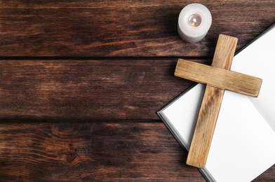 Cross, Bible and burning candle on wooden background, flat lay with space for text. Christian religion