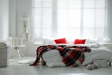 Comfortable bed with warm checkered plaid in stylish room interior