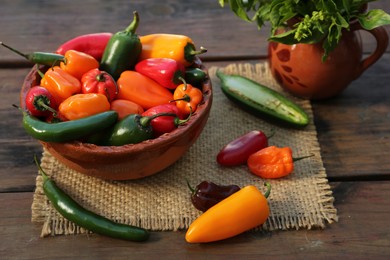 Photo of Many different ripe chili peppers on wooden table