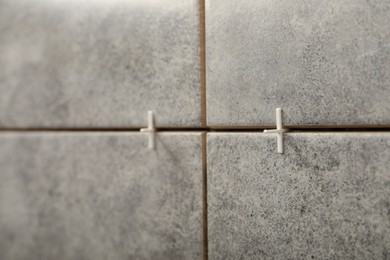 Photo of Stylish tiles with spacers on wall in room