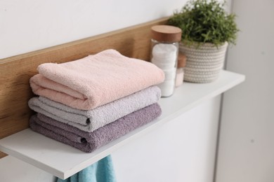 Photo of Fresh towels, houseplant and toiletries on shelf indoors