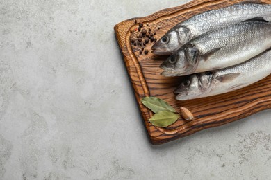 Tasty sea bass fish with spices on grey textured table, top view. Space for text