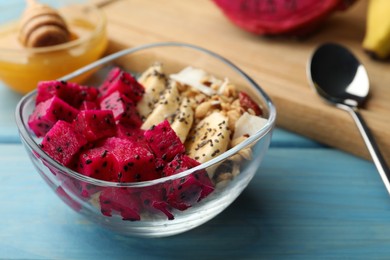 Bowl of granola with pitahaya and banana on light blue wooden table, closeup