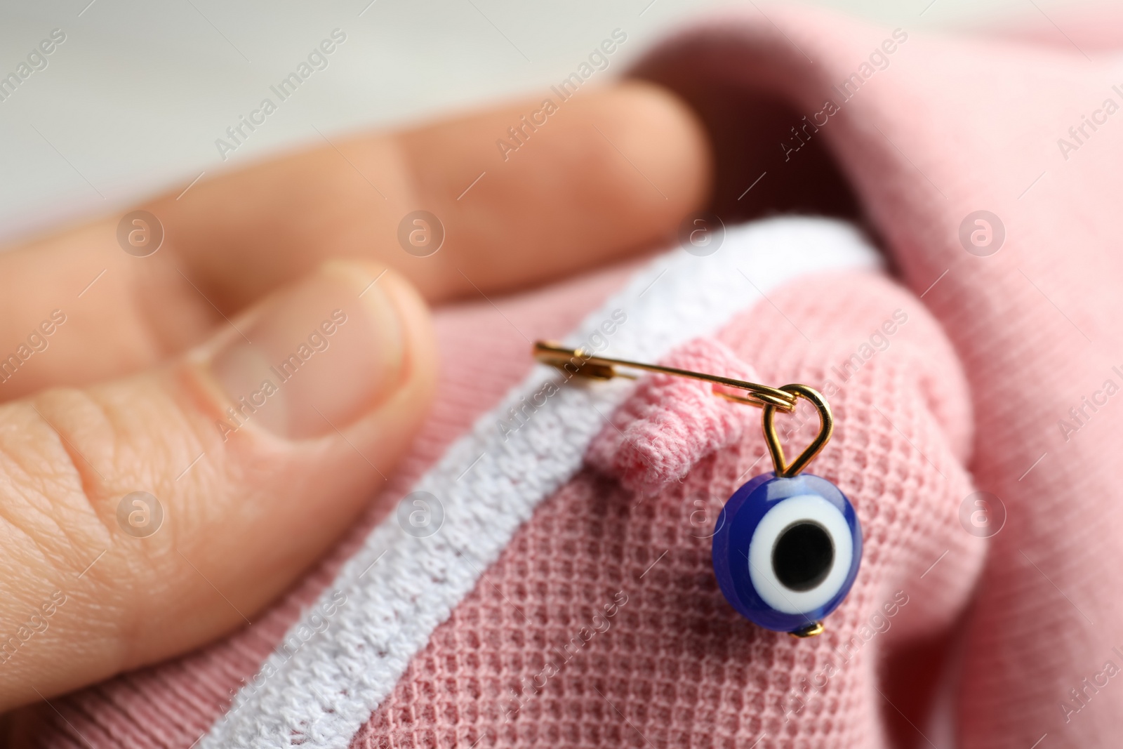 Photo of Woman holding clothing with evil eye safety pin, closeup