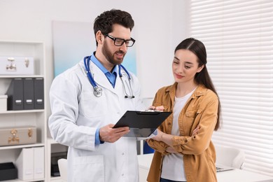 Doctor with clipboard consulting patient during appointment in clinic