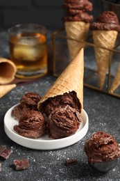 Photo of Tasty ice cream scoops, chocolate crumbs and waffle cones on dark textured table