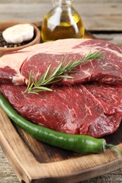 Photo of Fresh raw beef cut with spices and oil on wooden table, closeup