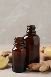 Photo of Glass bottles of essential oil and ginger root on beige wooden table