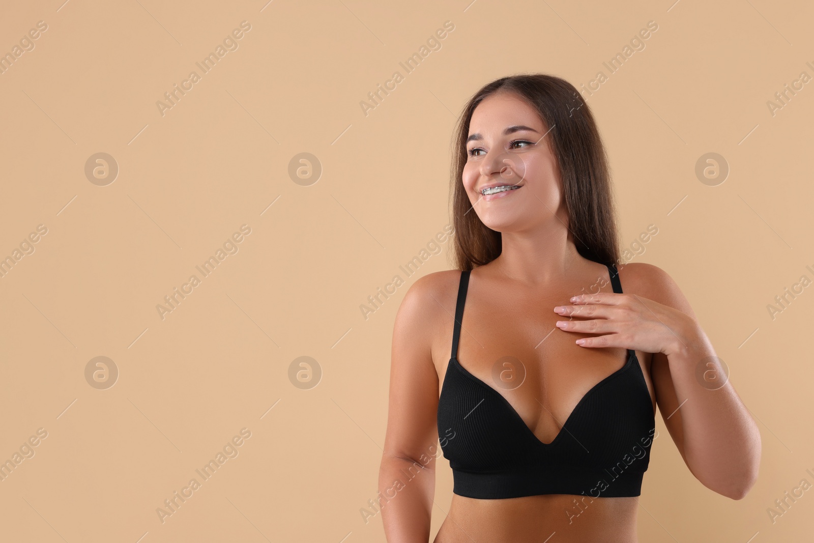 Photo of Portrait of young woman with beautiful breast on beige background. Space for text