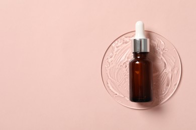 Photo of Bottle of cosmetic serum on pink background, top view. Space for text