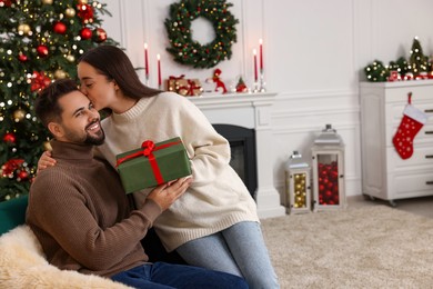 Photo of Beautiful young couple with Christmas gift at home