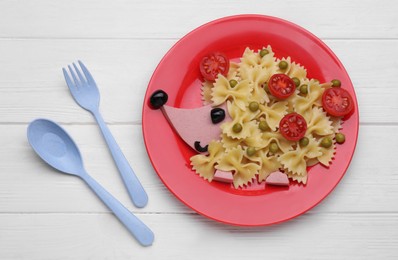 Creative serving for kids. Plate with cute hedgehog made of delicious pasta, sausages and tomatoes on white wooden table, flat lay