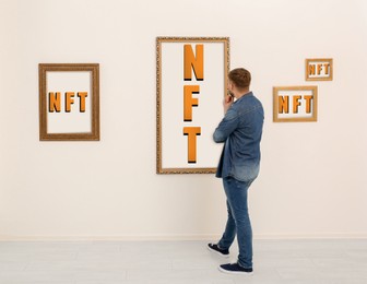 Image of Man at exhibition in gallery, back view. Pictures with abbreviations NFT