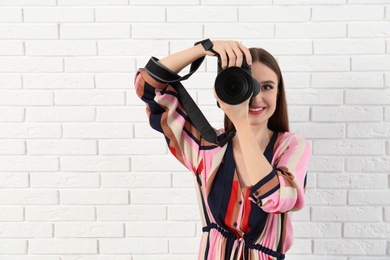 Professional photographer taking picture near white brick wall