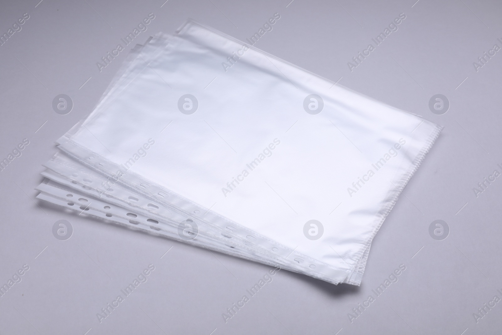 Photo of Punched pockets on light grey background. Document protection