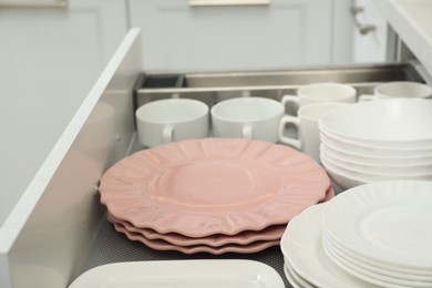 Photo of Clean plates, bowls and cups in drawer indoors