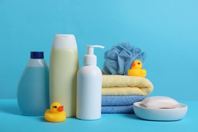 Photo of Baby cosmetic products, bath ducks, sponge and towels on light blue background