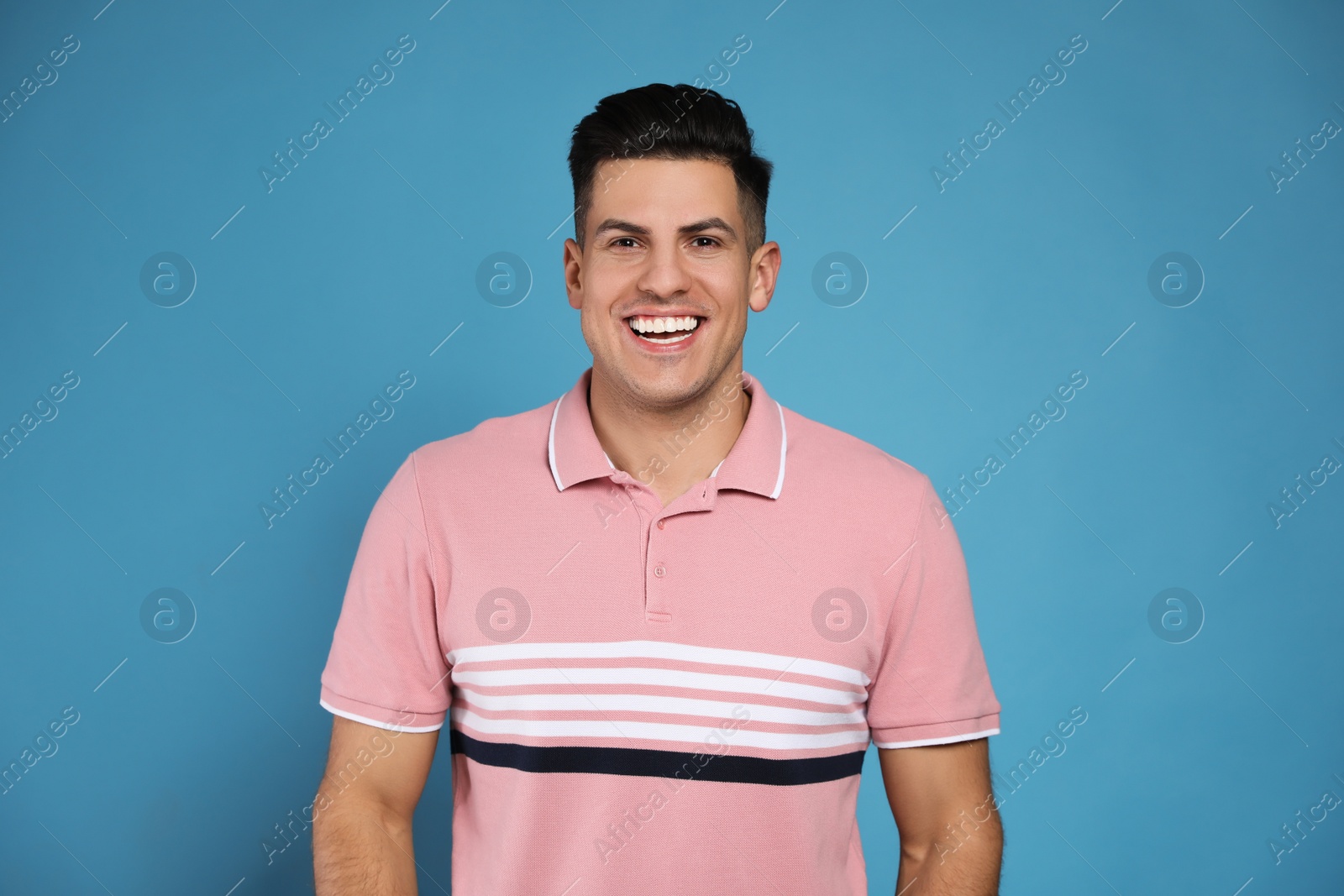 Photo of Handsome man laughing on light blue background. Funny joke