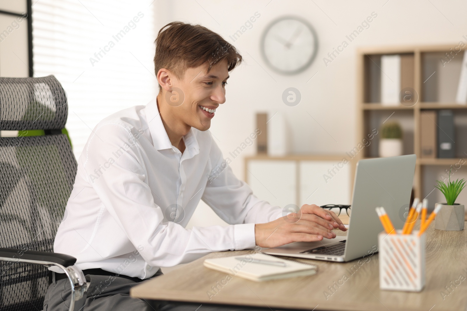 Photo of Man watching webinar at wooden table in office