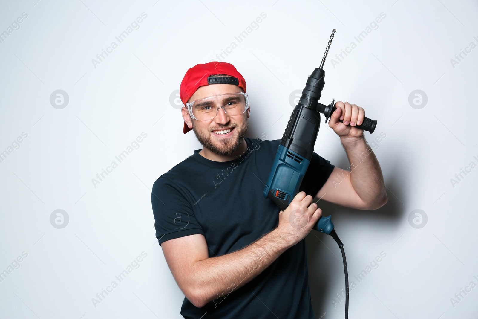 Photo of Young working man with rotary hammer on light background