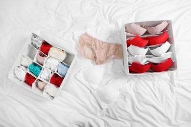 Photo of Organizers with stylish women's underwear on bed, flat lay