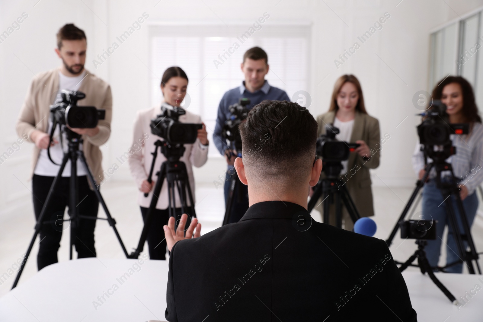 Photo of Businessman giving interview to journalists at official event, back view