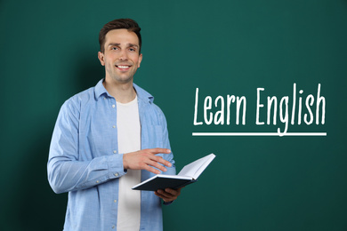 Image of Young English teacher with book near chalkboard
