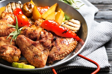 Photo of Delicious barbecued chicken wings with garnish served in wok on table