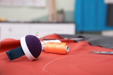 Photo of Fabric and sewing tools on table in tailor workshop, closeup