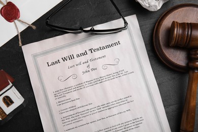 Photo of Last will and testament near house model, glasses, gavel on black table, flat lay