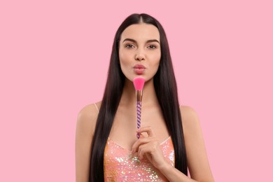Photo of Beautiful woman with makeup brush on pink background