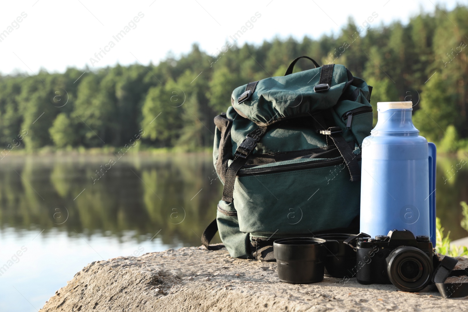 Photo of Set of camping equipment on rock near lake