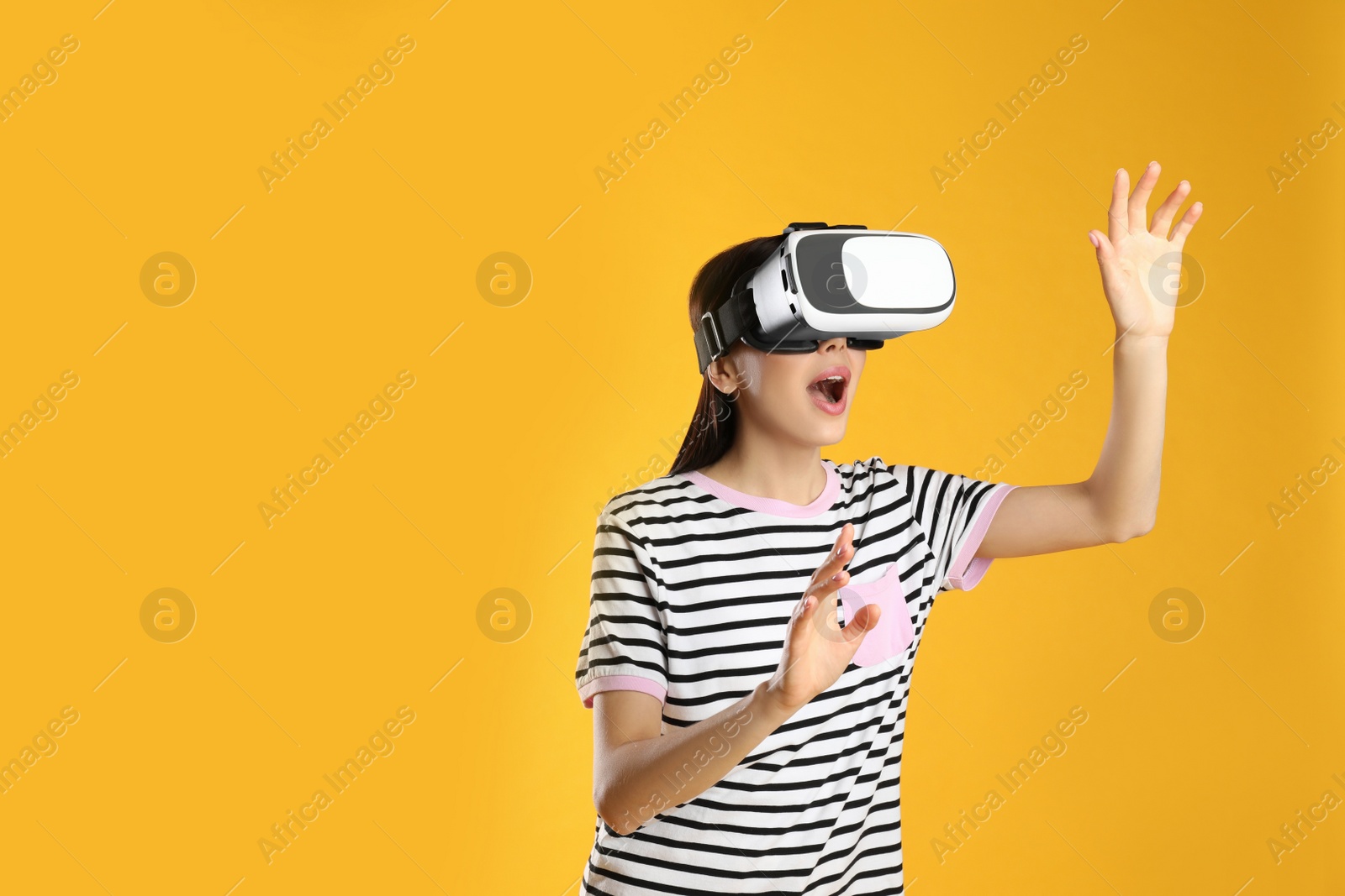 Photo of Woman using virtual reality headset on yellow background