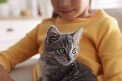 Photo of Cute little girl with kitten on sofa at home, closeup. Childhood pet