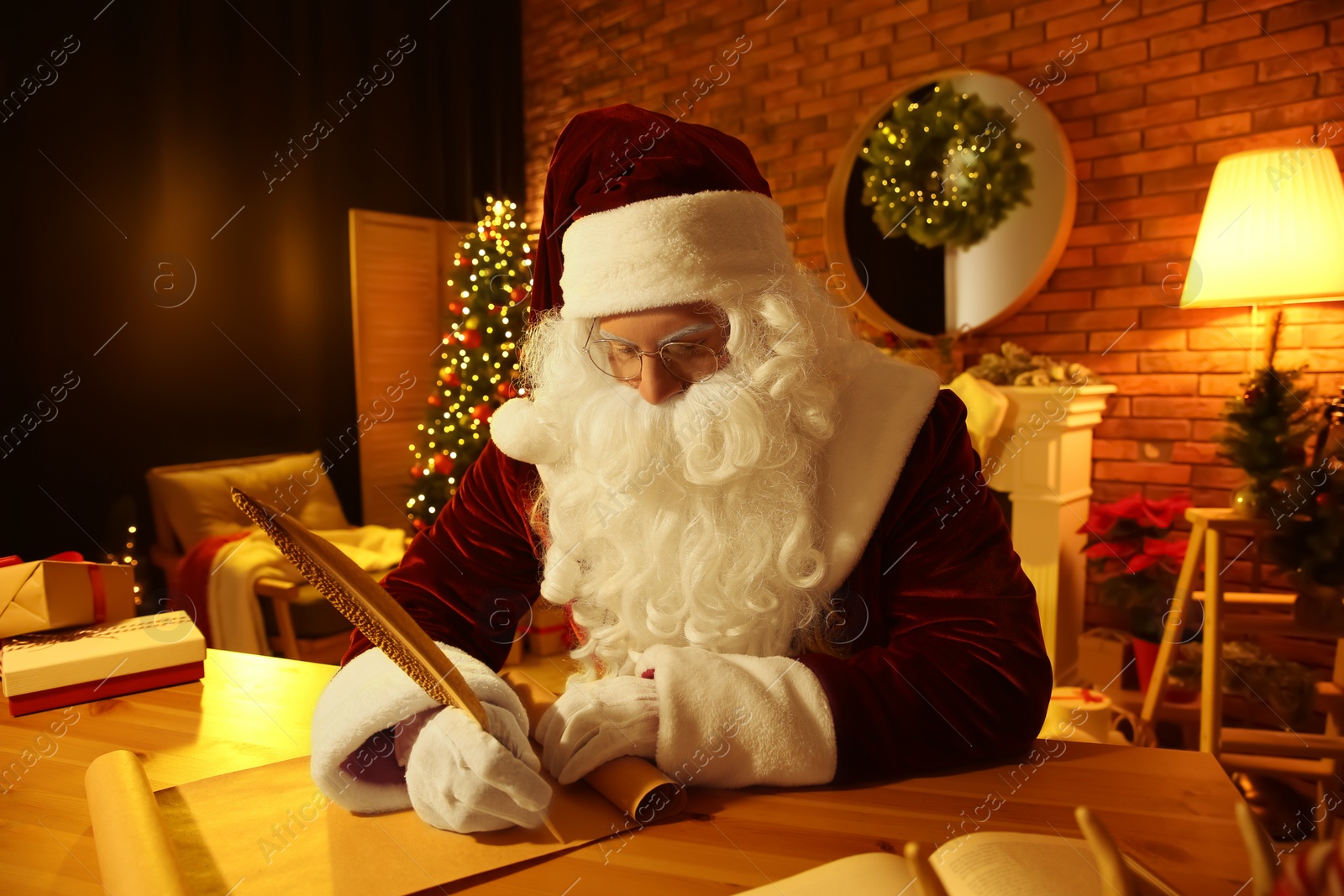 Photo of Santa Claus writing letter at table indoors