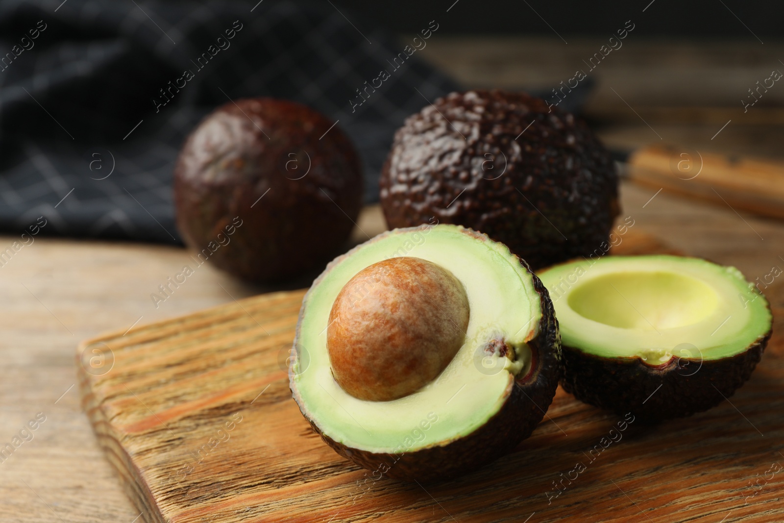 Photo of Halves of delicious ripe avocado on wooden board