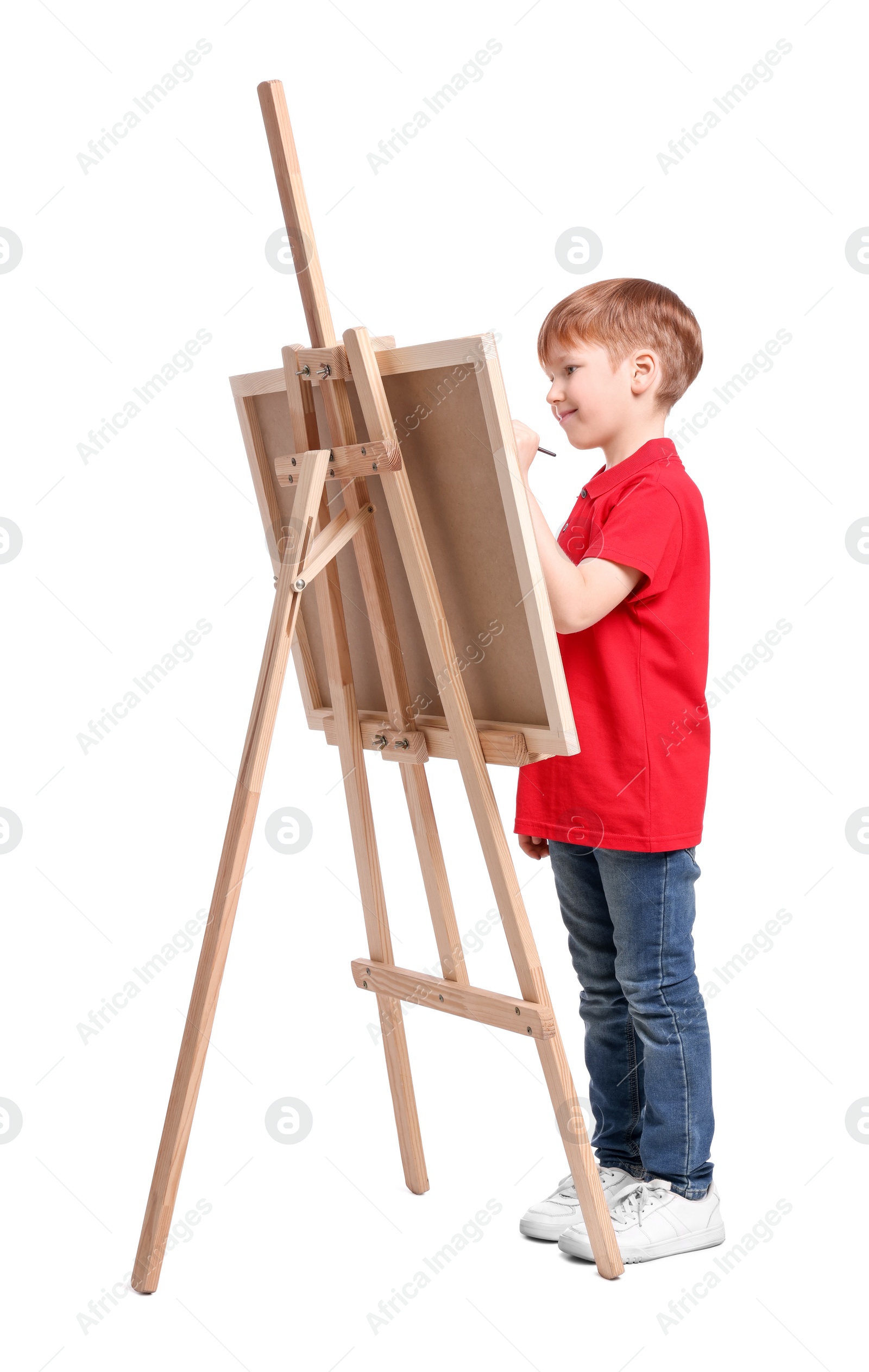 Photo of Little boy painting against white background. Using easel to hold canvas