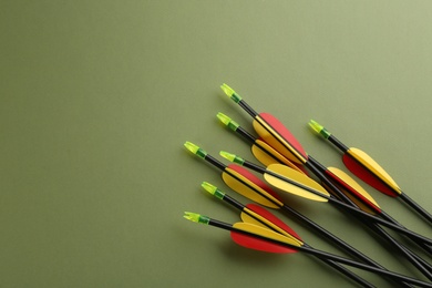 Photo of Plastic arrows on olive background, flat lay with space for text. Archery sports equipment