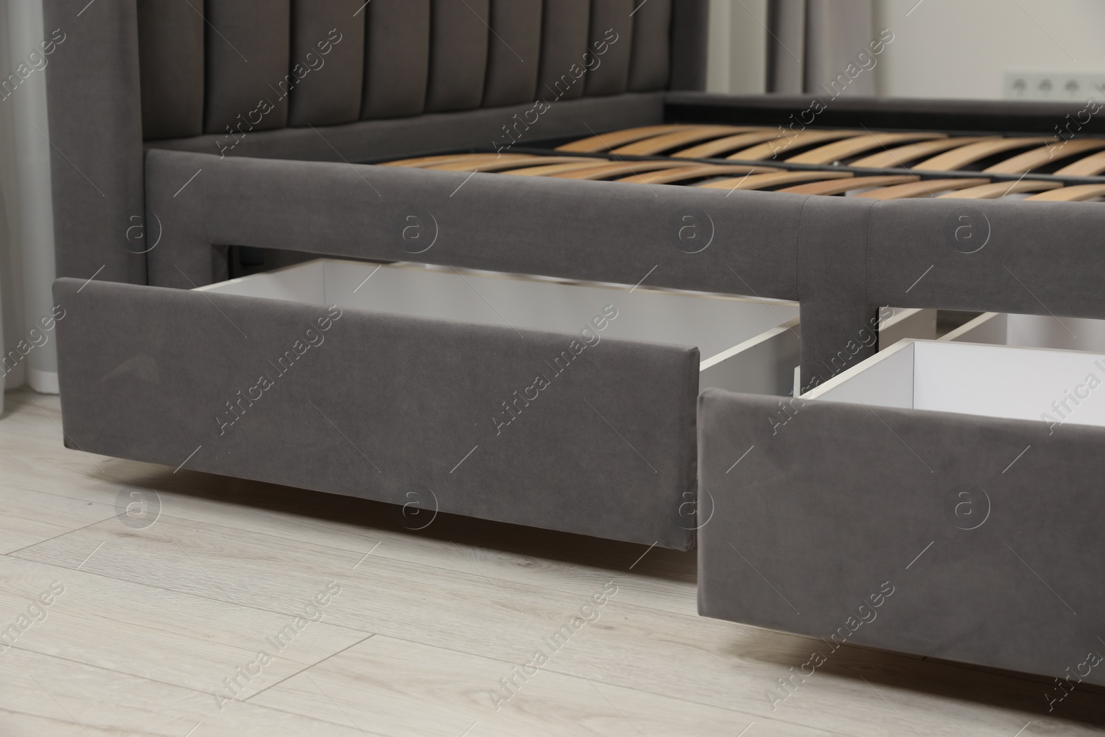 Photo of Storage drawers for bedding under modern bed in room, closeup