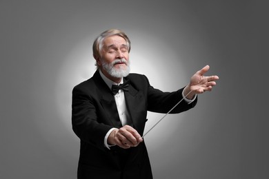 Professional conductor with baton on grey background