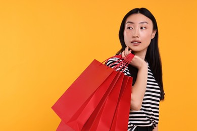 Photo of Beautiful woman with shopping bags on yellow background. Space for text