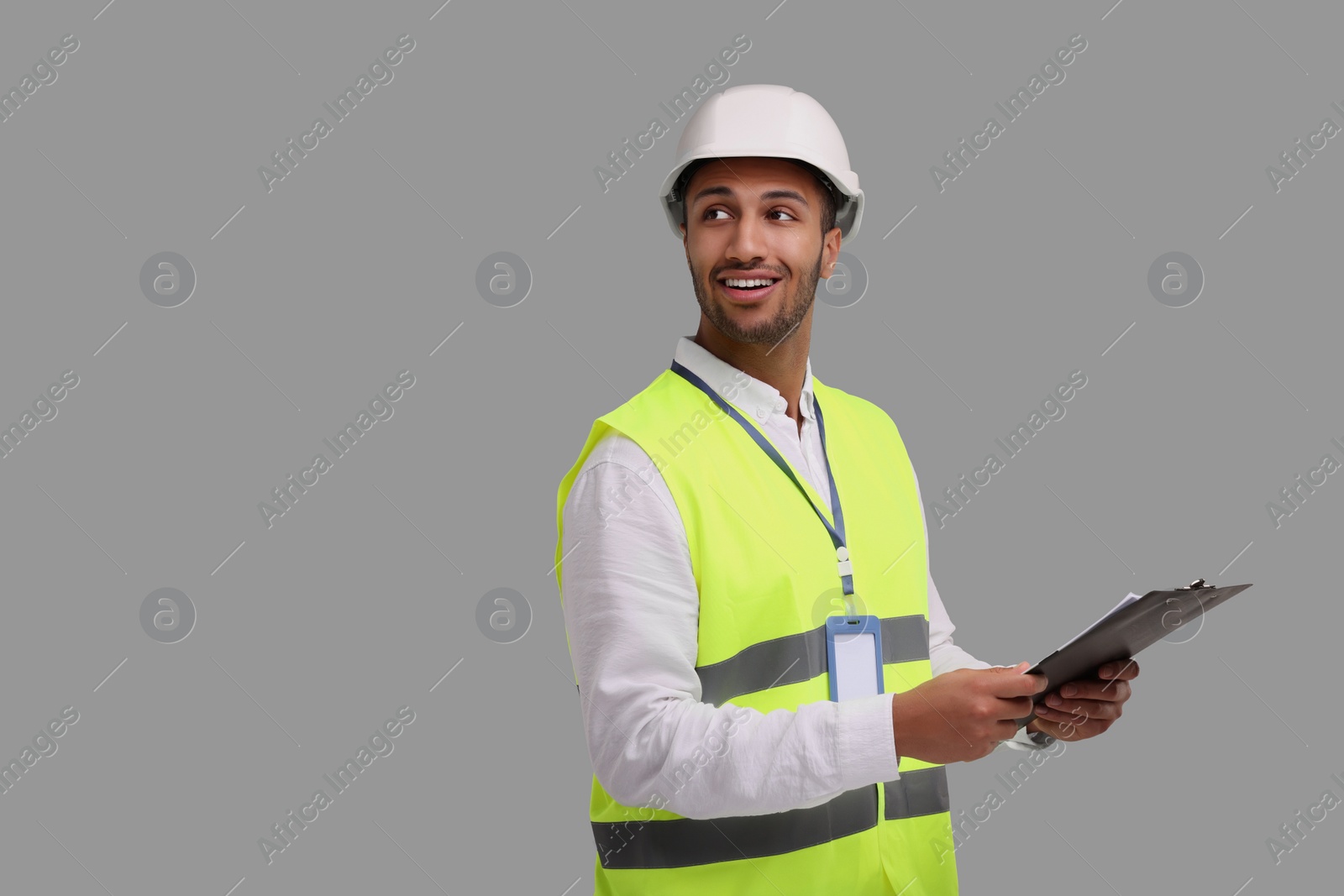 Photo of Engineer in hard hat holding clipboard on grey background, space for text