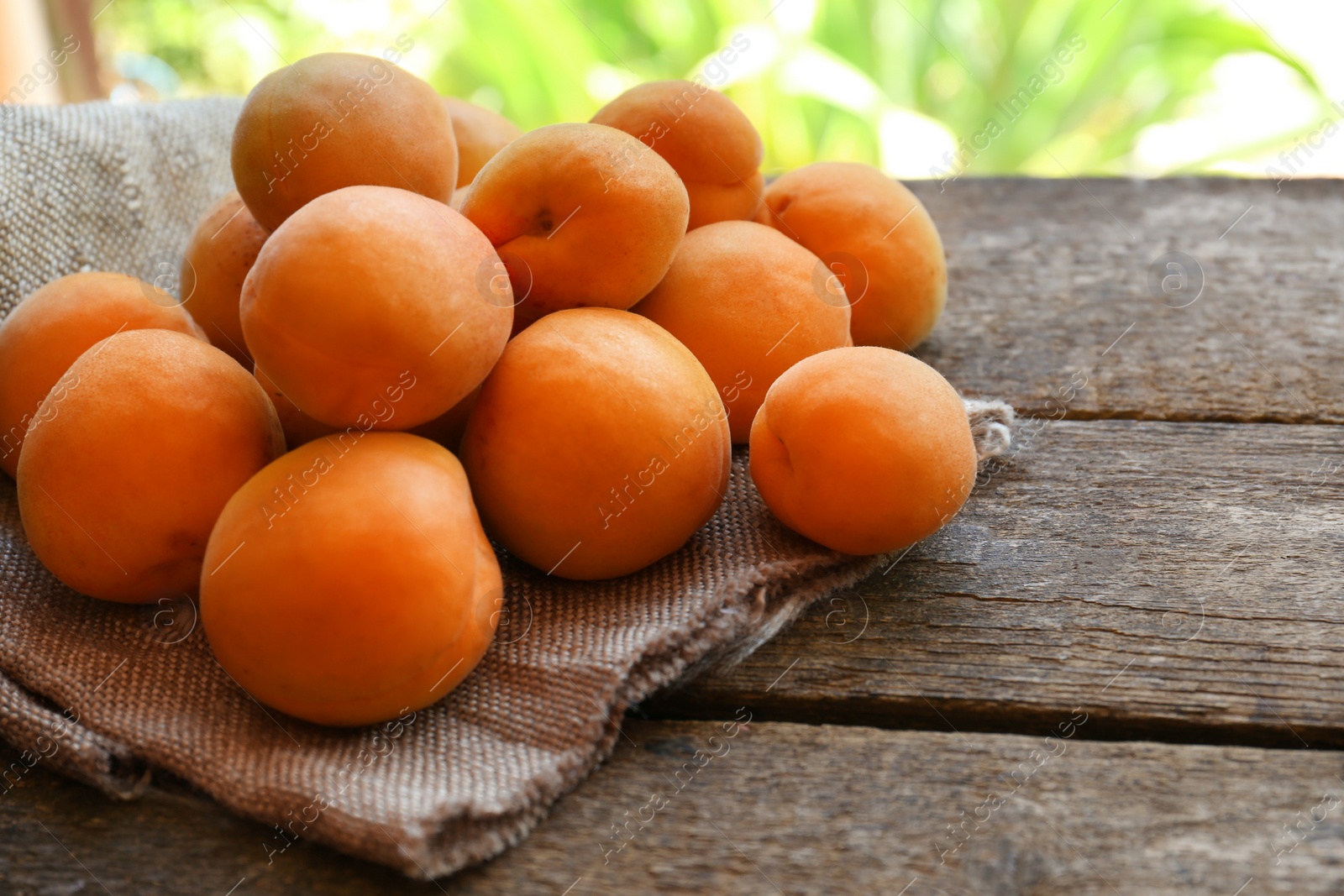 Photo of Delicious ripe apricots with napkin on wooden table, closeup