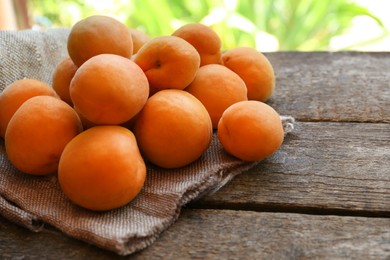 Delicious ripe apricots with napkin on wooden table, closeup