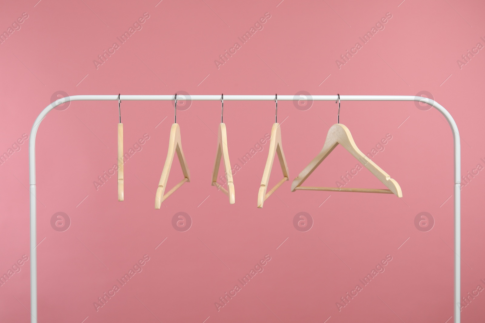 Photo of Empty clothes hangers on rack against pink background