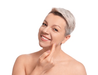 Photo of Mature woman applying face cream on white background