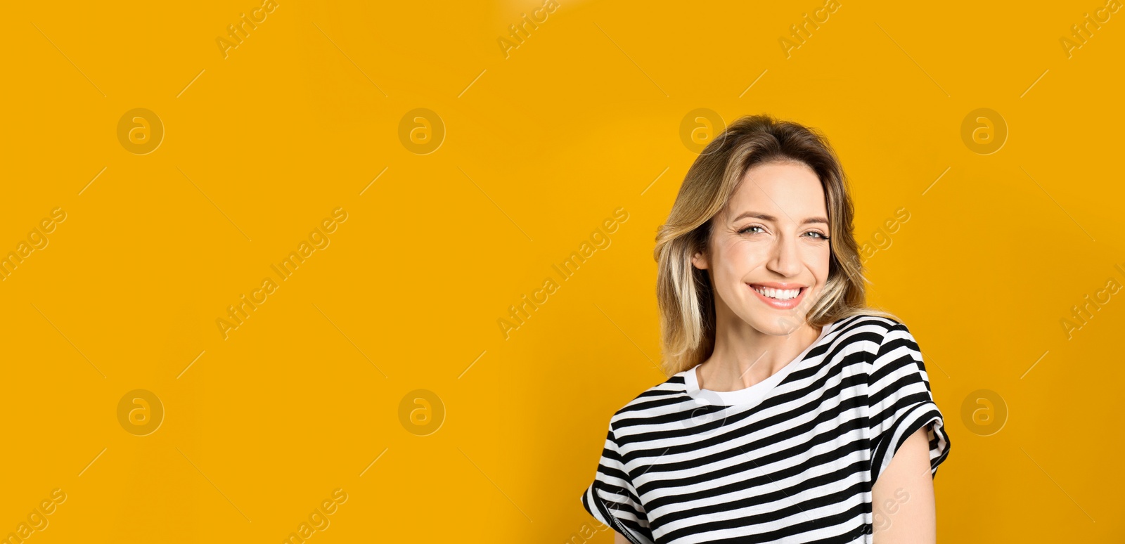 Photo of Portrait of happy young woman with beautiful blonde hair and charming smile on yellow background