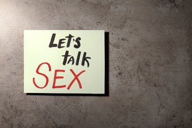 Photo of Note with phrase "LET'S TALK SEX" on stone background, top view