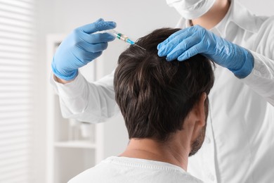 Photo of Trichologist giving injection to patient in clinic, closeup