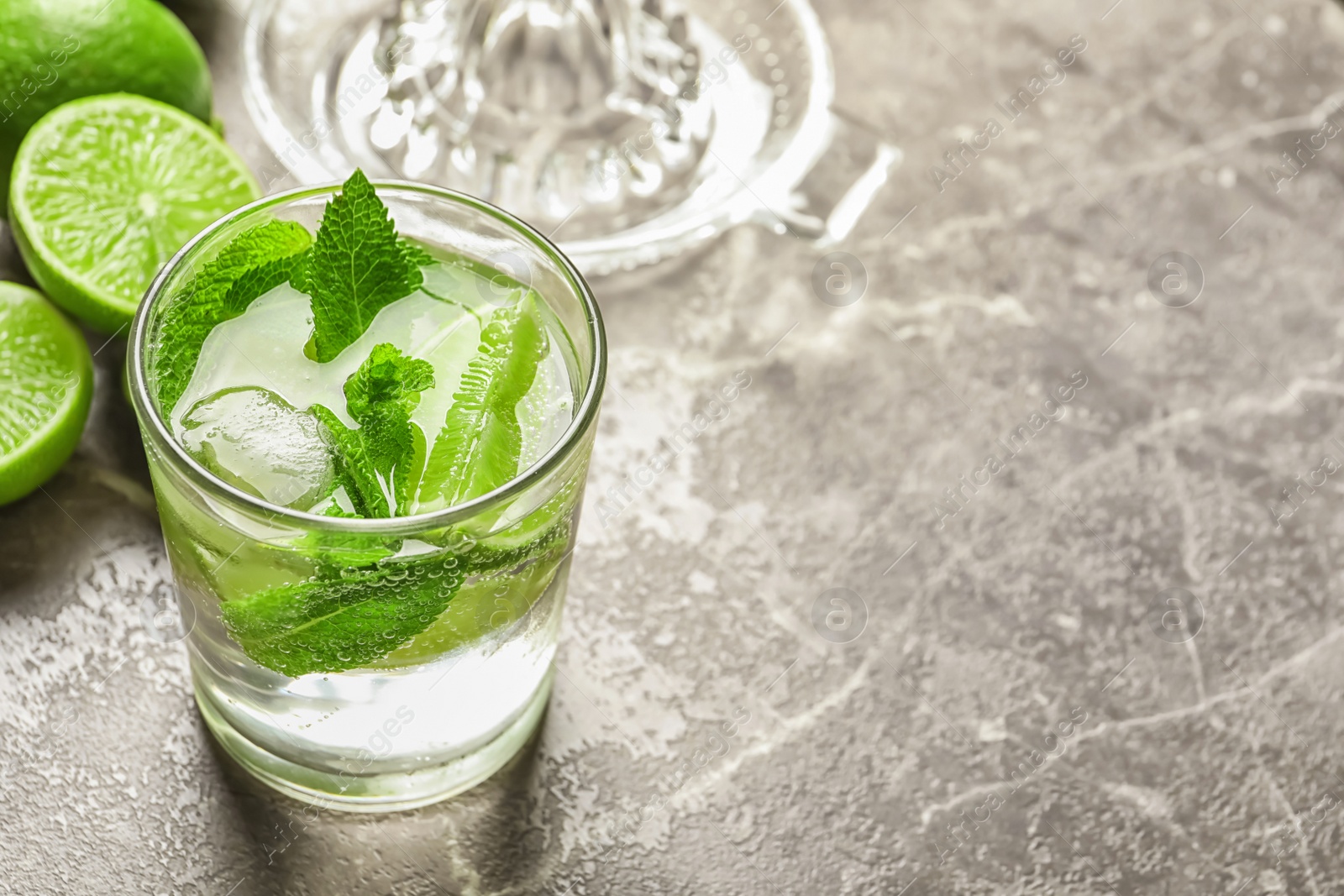 Photo of Refreshing beverage with mint and lime in glass on table